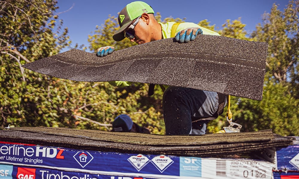 man picking up shingles from package